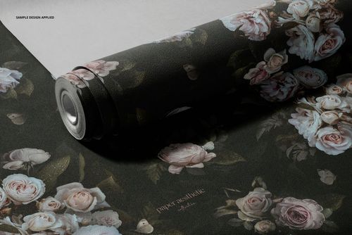 Dark floral non-woven vinyl wallpaper mockup featuring pink and white roses, displayed partially unrolled on a flat surface.