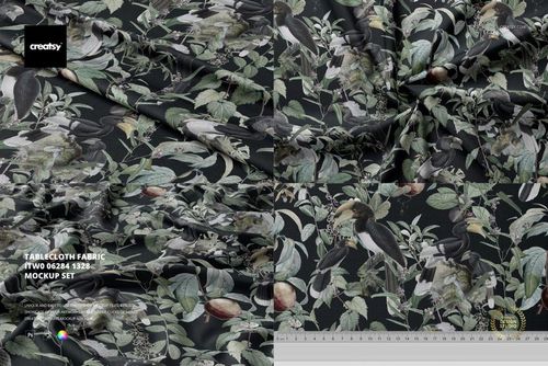 Botanical tablecloth fabric mockup displaying a leafy and bird motif on a dark surface, seen from above.