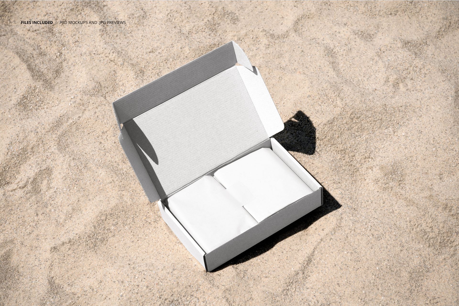 Rectangular mailing box mockup with open lid, showing white packaging inside, placed on sandy surface.