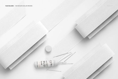 Top view of several white cotton ribbons arranged on flat paddles with a spool and scattered strips on a light surface.