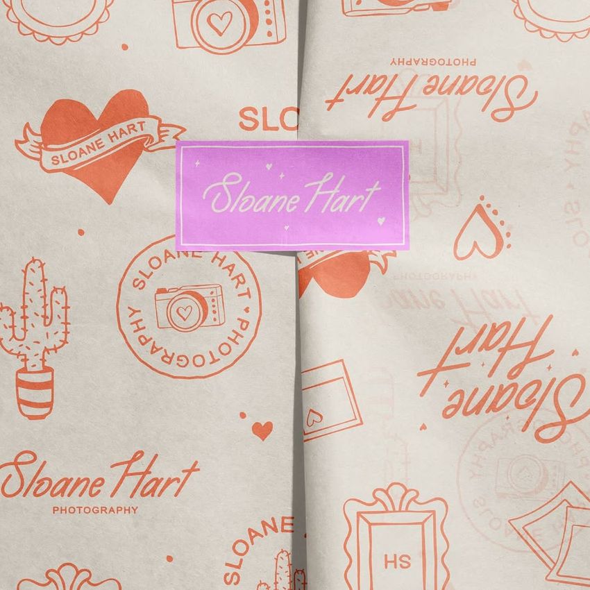 Wrapping paper mockup featuring a cream background with orange illustrations and text, folded with a purple sticker seal.
