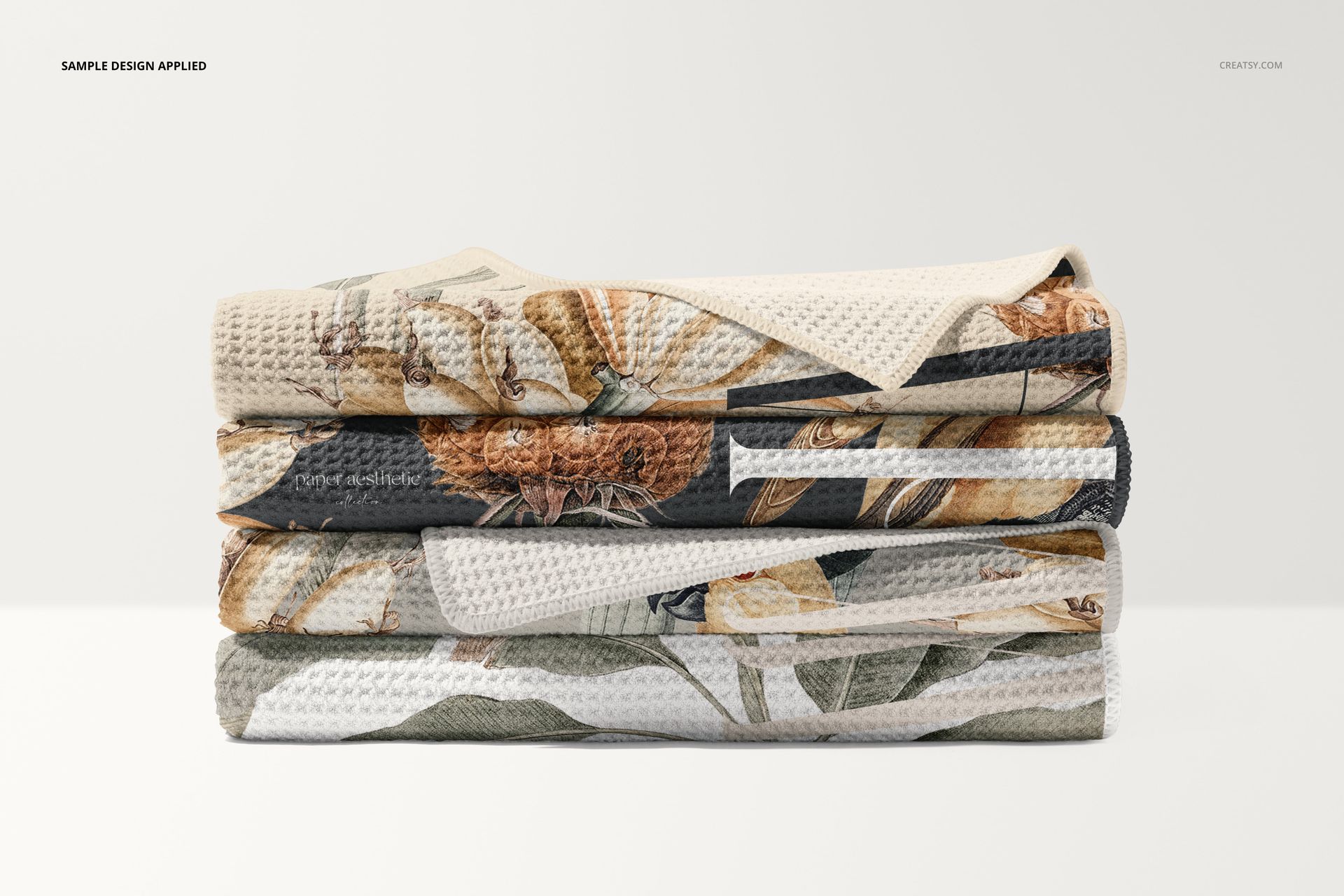 PSD mockup of four stacked waffle beach towels with textured surfaces and assorted nature-inspired designs.