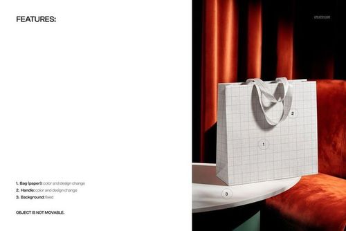 Luxury paper shopping bag with ribbon handles mockup shown in front view on a table, set against a red curtain background.