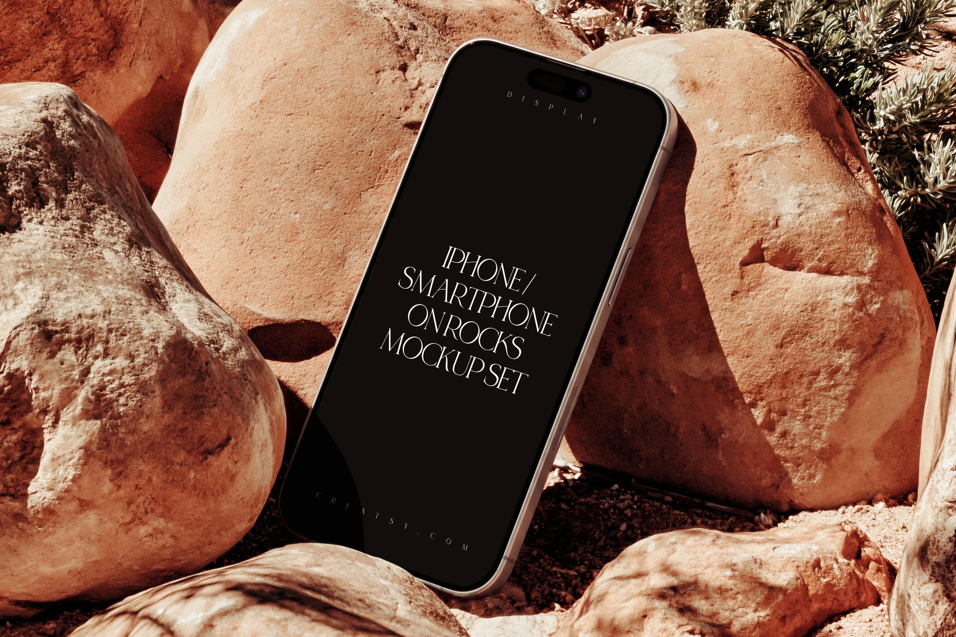 PSD mockup of an iPhone smartphone standing vertically on natural rocks, surrounded by earthy tones and sunlight.