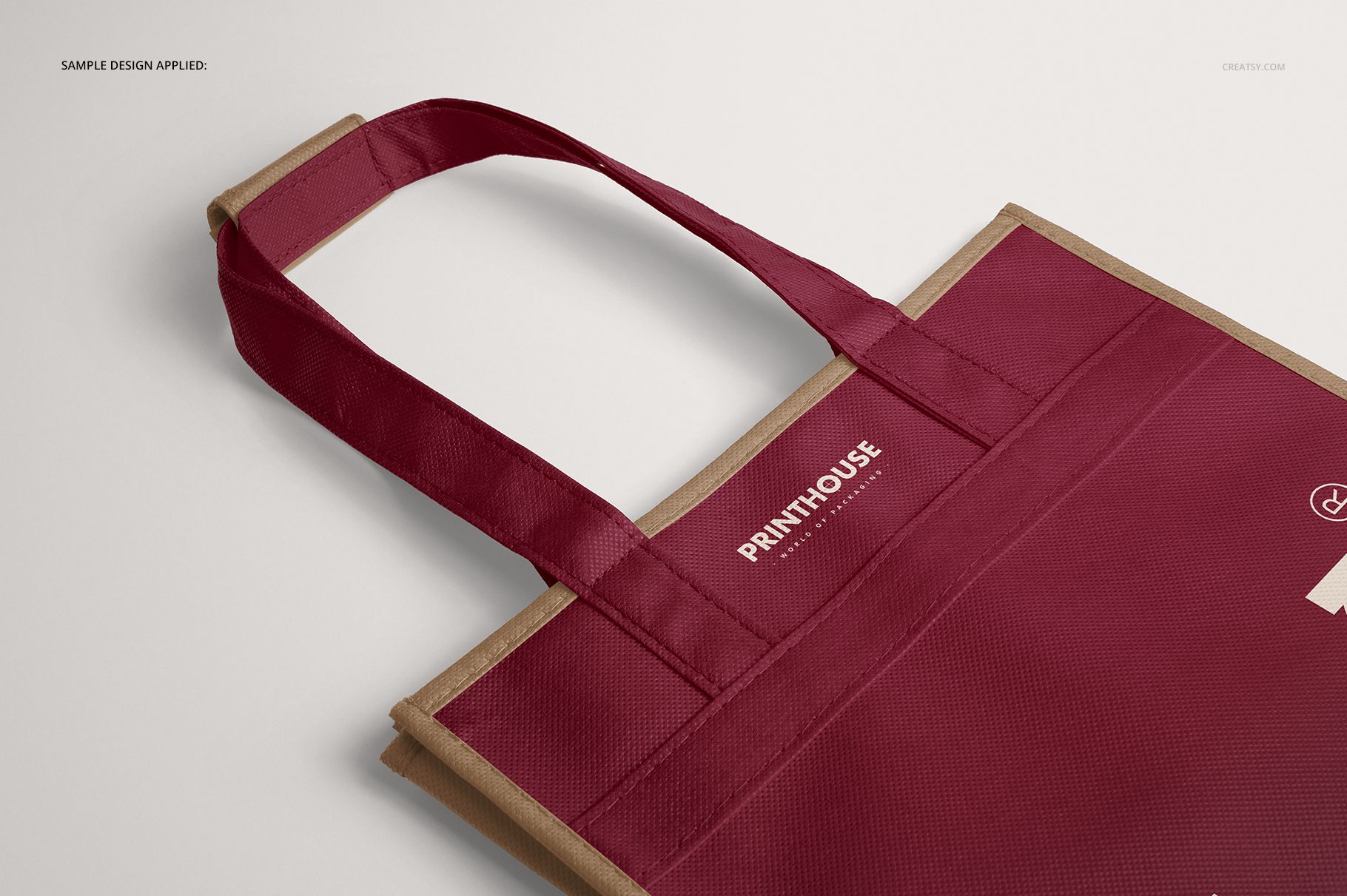 Close-up front view of a six-bottle non-woven wine tote bag mockup in burgundy with beige handles on a light background.