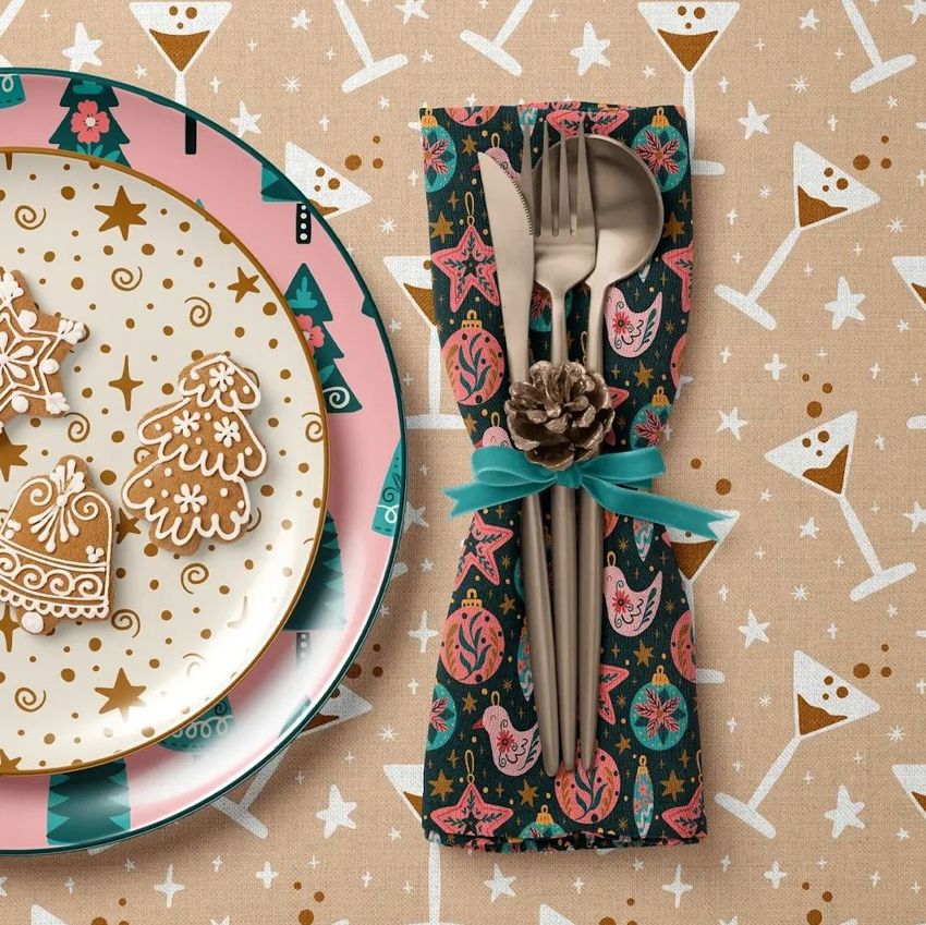 Plate, napkin, and tablecloth mockup featuring festive Christmas patterns, gingerbread cookies, and cutlery with a pinecone accent.