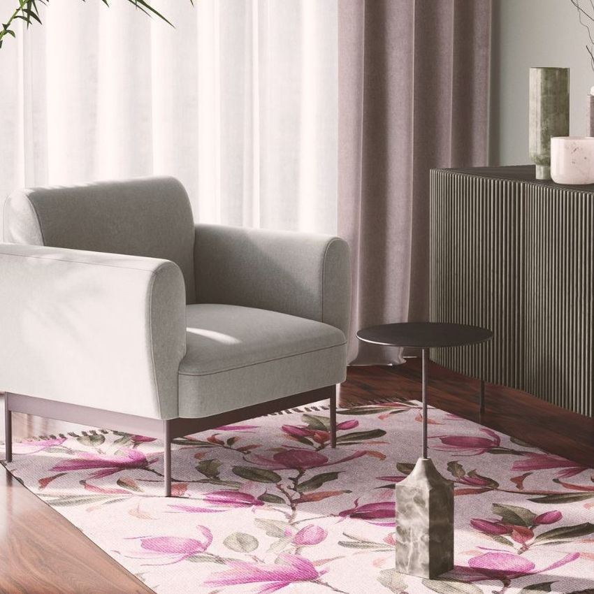 Mid-century modern interior mockup with a light gray armchair, black sideboard, and a floral patterned rug in pink and green tones.