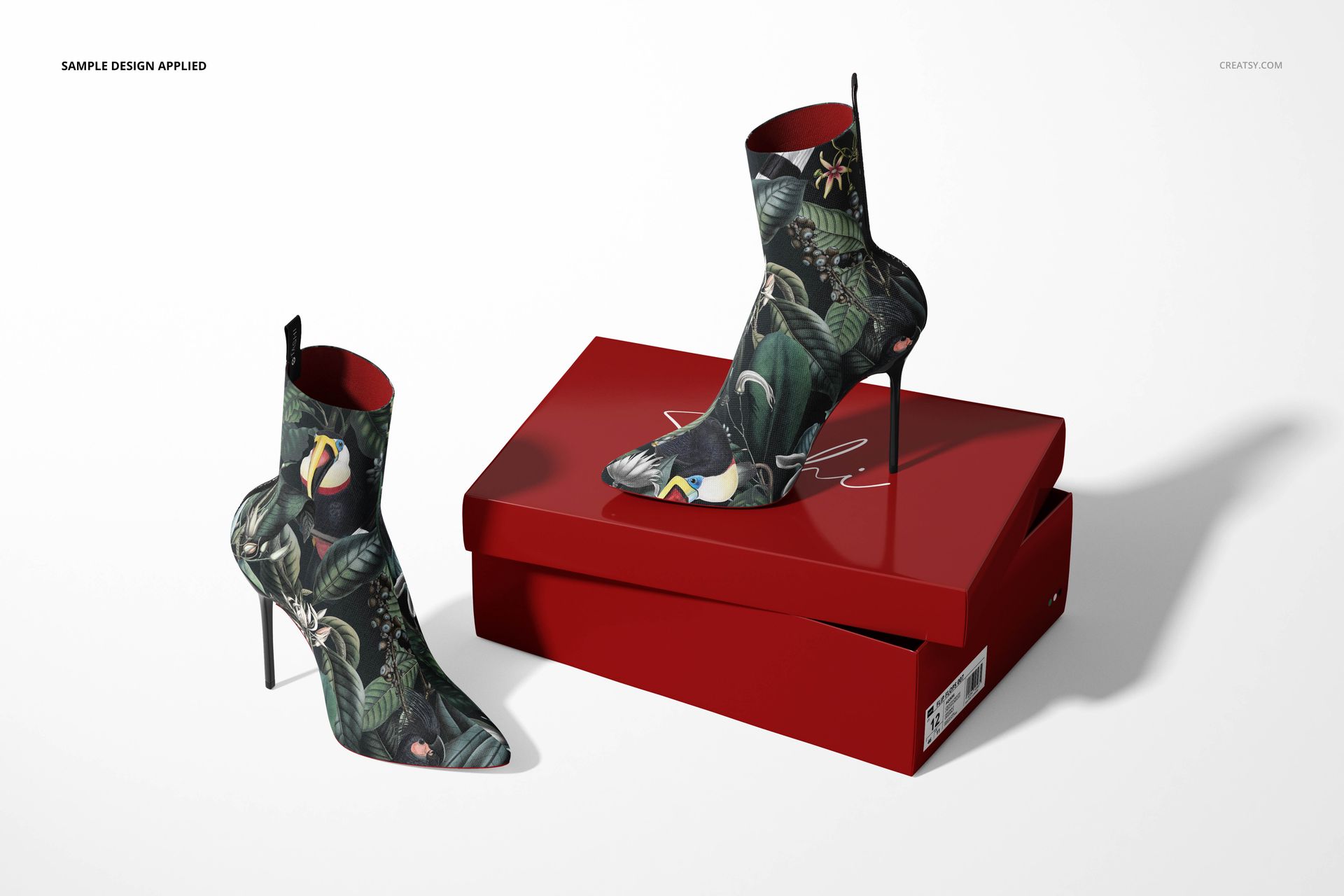PSD mockup of patterned ankle boots with stiletto heels, placed on a stacked red shoebox in a well-lit scene.