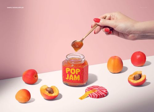 PSD mockup of a jam jar with bright label, apricots, and a spoon on a white tabletop with soft shadows.