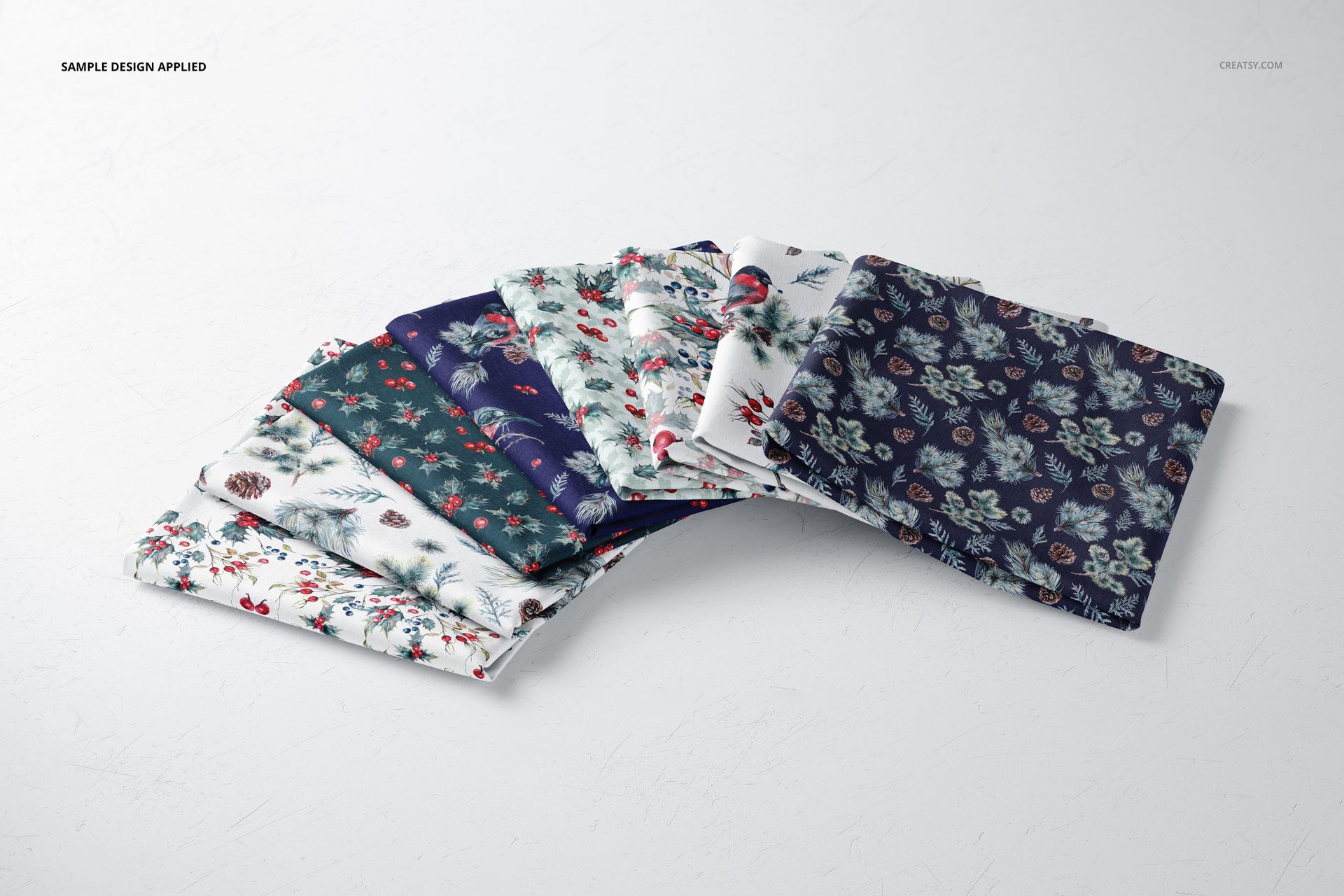 PSD mockup showing multiple folded fabric samples featuring colorful botanical prints, arranged in a fan shape.