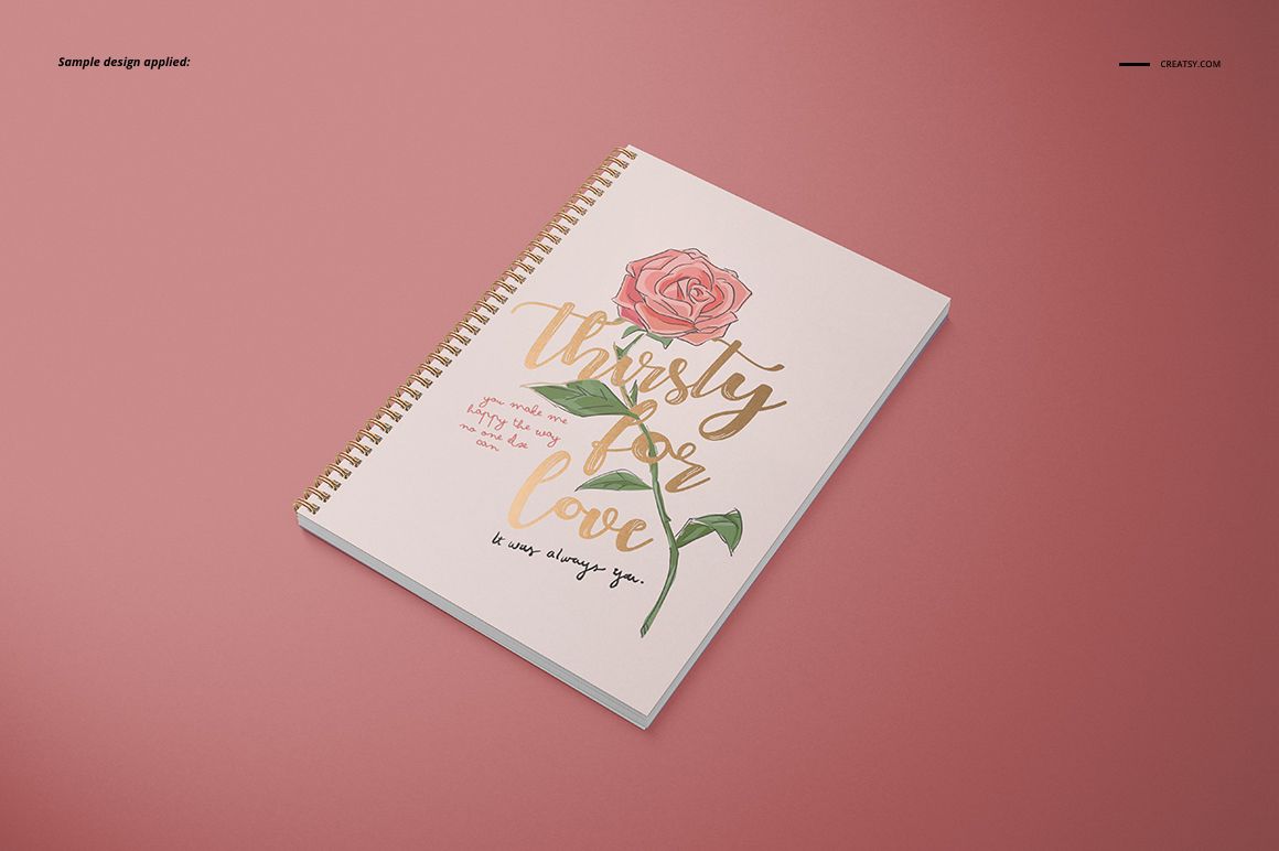 Spiral-bound A4 notebook mockup with square holes and illustrated rose cover, displayed on a solid pink background.