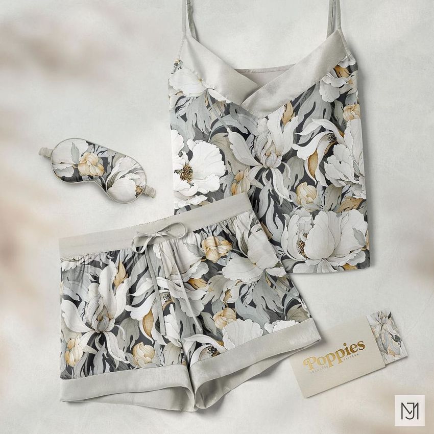 Short silk pajama mockup set featuring a camisole, shorts, and sleep mask with a white and beige poppy floral pattern on a light background.