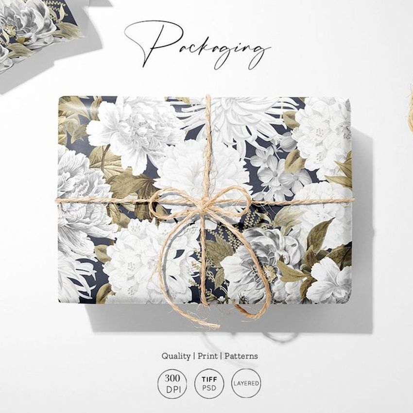 Gift wrapping paper mockup featuring a rectangular box wrapped in floral patterned paper with twine tied in a bow.