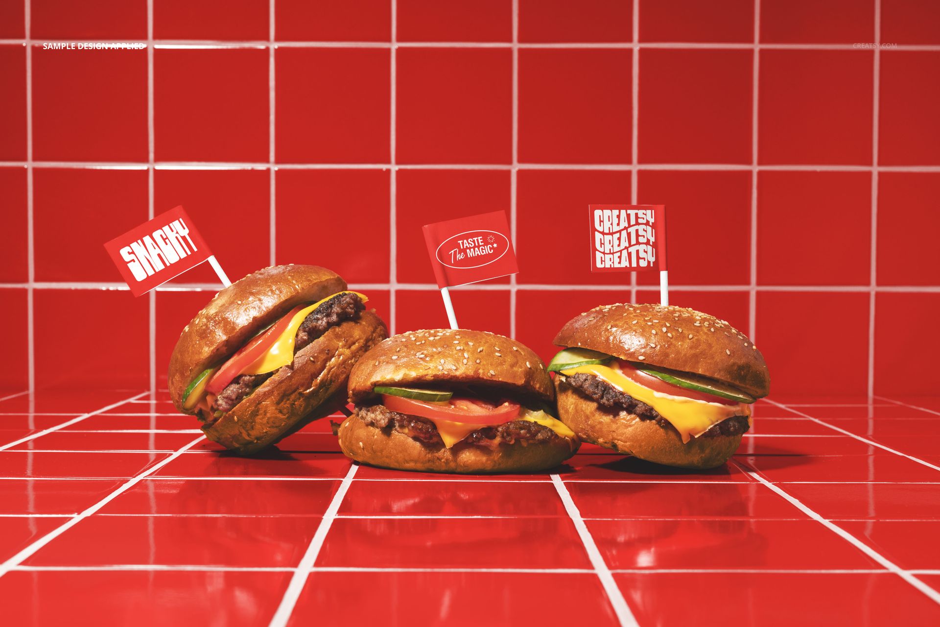 PSD mockup showing three classic burgers with flags, arranged on a glossy red tile countertop.