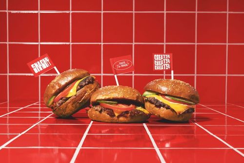 PSD mockup showing three classic burgers with flags, arranged on a glossy red tile countertop.