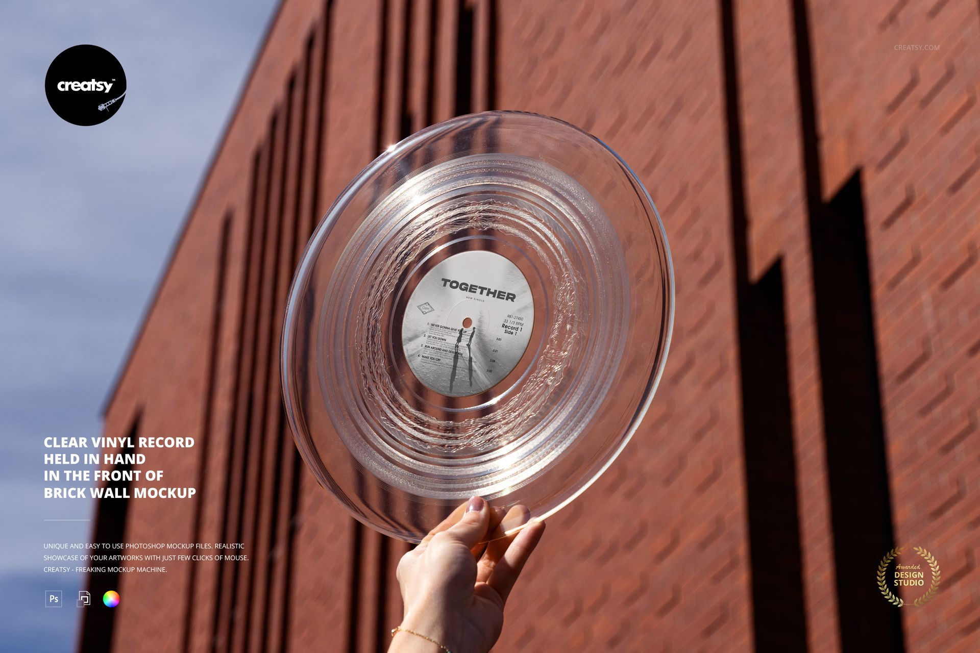 Transparent vinyl record mockup shown being held by a hand against a tall red brick building exterior.