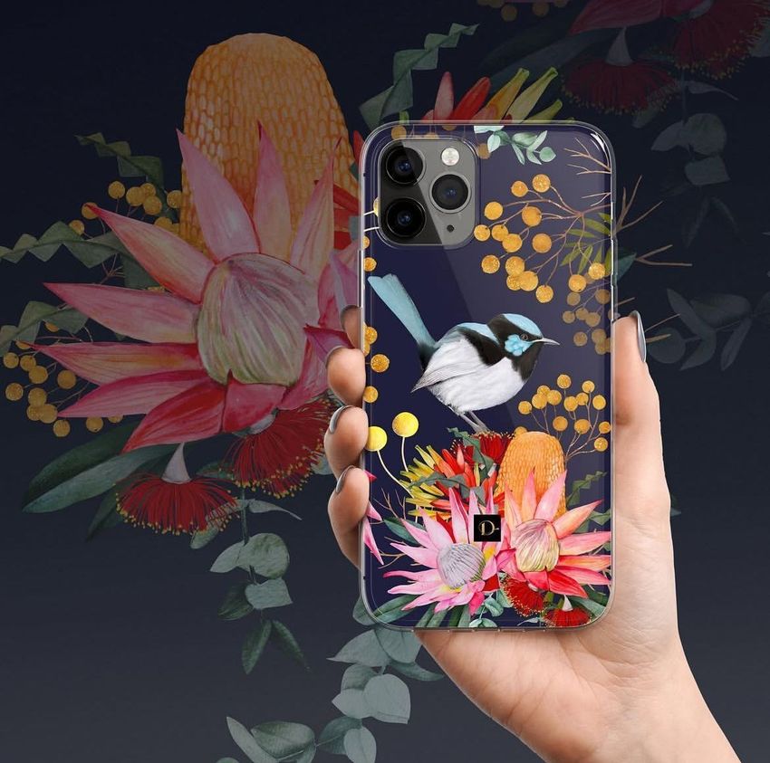 Hand holding an iPhone 11 Pro clear case mockup featuring a colorful floral and bird illustration on a dark background.
