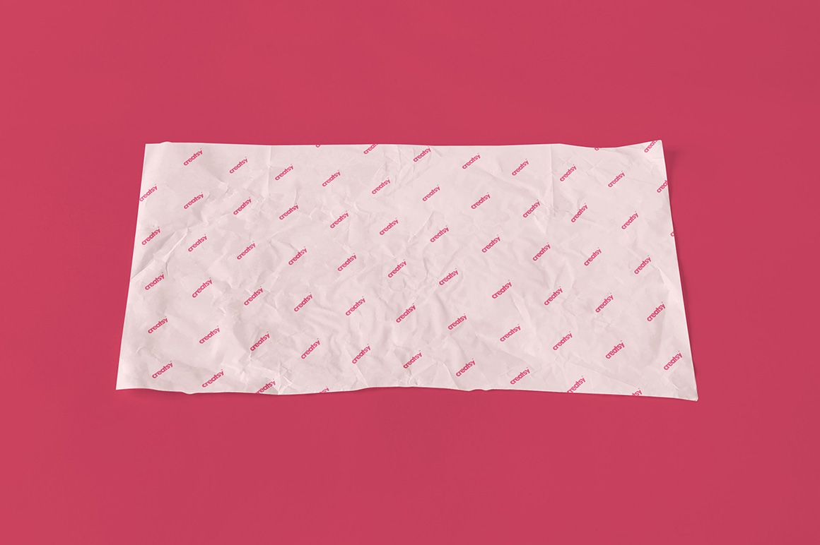 Top view of a white wrapping paper mockup with a diagonal red pattern, set on a plain pink background.