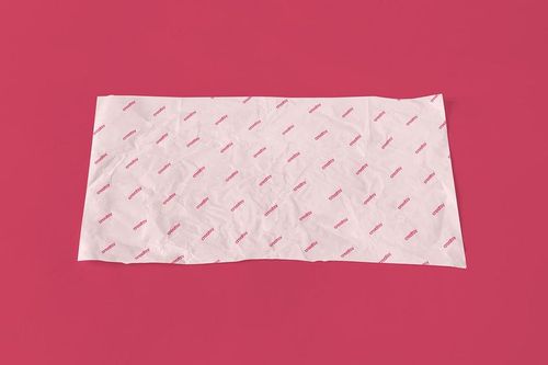 Top view of a white wrapping paper mockup with a diagonal red pattern, set on a plain pink background.