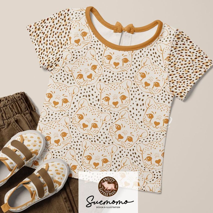 Kids t-shirt mockup featuring a beige shirt with cheetah faces and dotted patterns, paired with brown jeans and matching shoes.