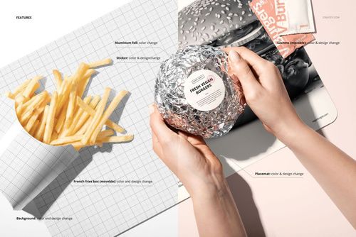 Top view of a fast food placemat mockup with a wrapped burger in foil and a container of French fries on a grid background.