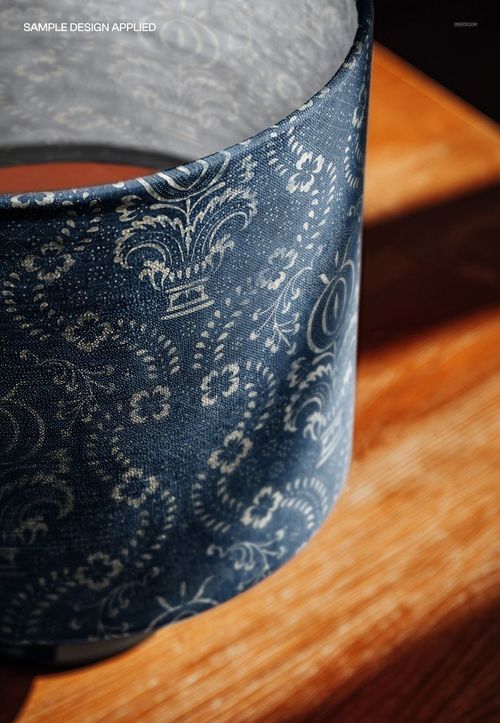 Top angle view of a drum lampshade mockup with a blue fabric exterior featuring an ornate white floral pattern.