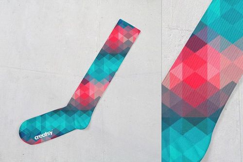 Colorful knee high sock mockup featuring a polygonal design in shades of teal, red, and blue on a plain background.