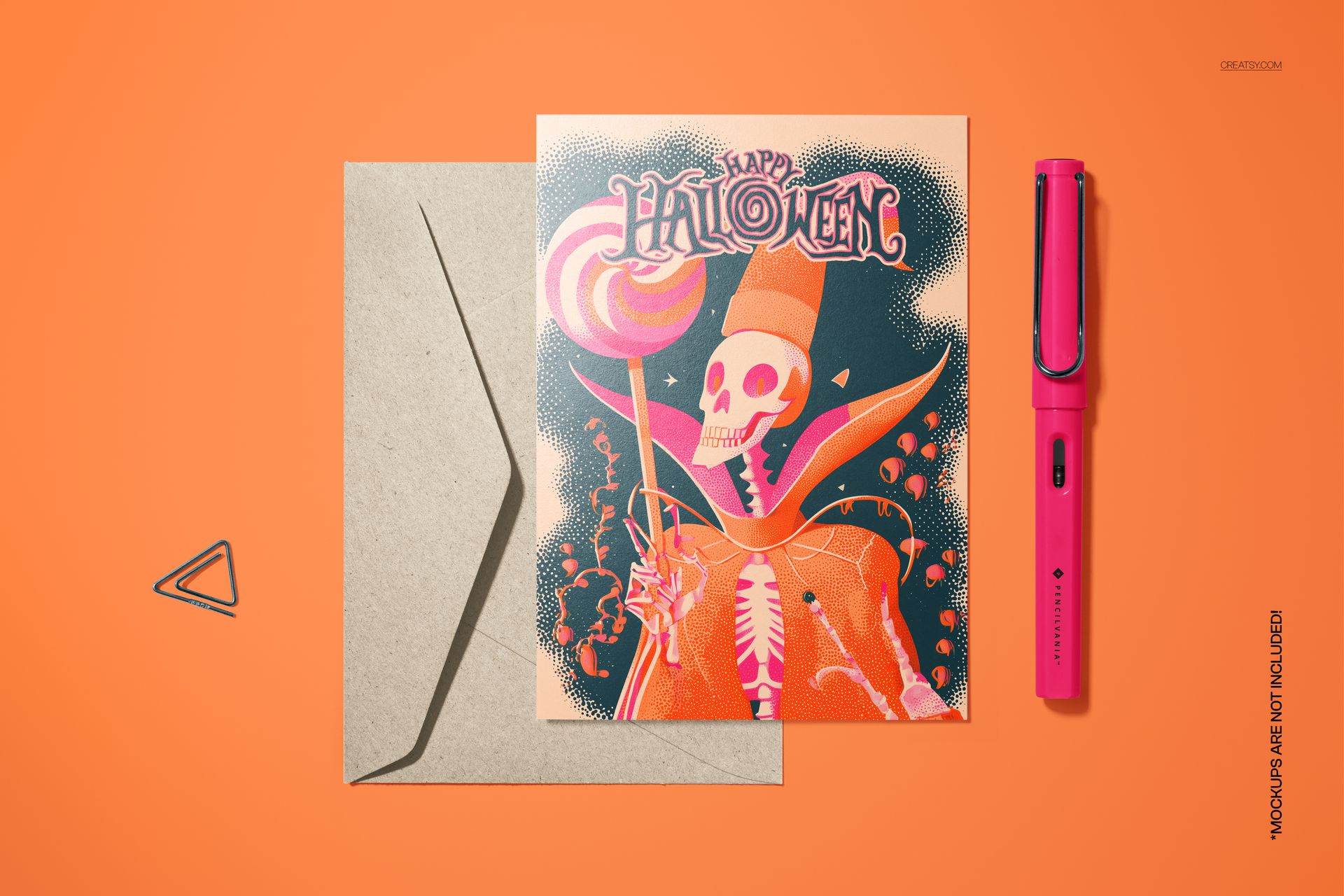 Halloween card mockup with a vintage-style pink skeleton wizard design, shown with a kraft envelope and pink pen on orange surface.