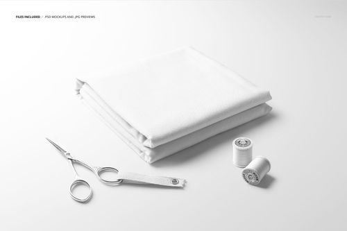White folded fabric mockup set shown from a front angle, accompanied by sewing scissors and thread spools on a plain background.