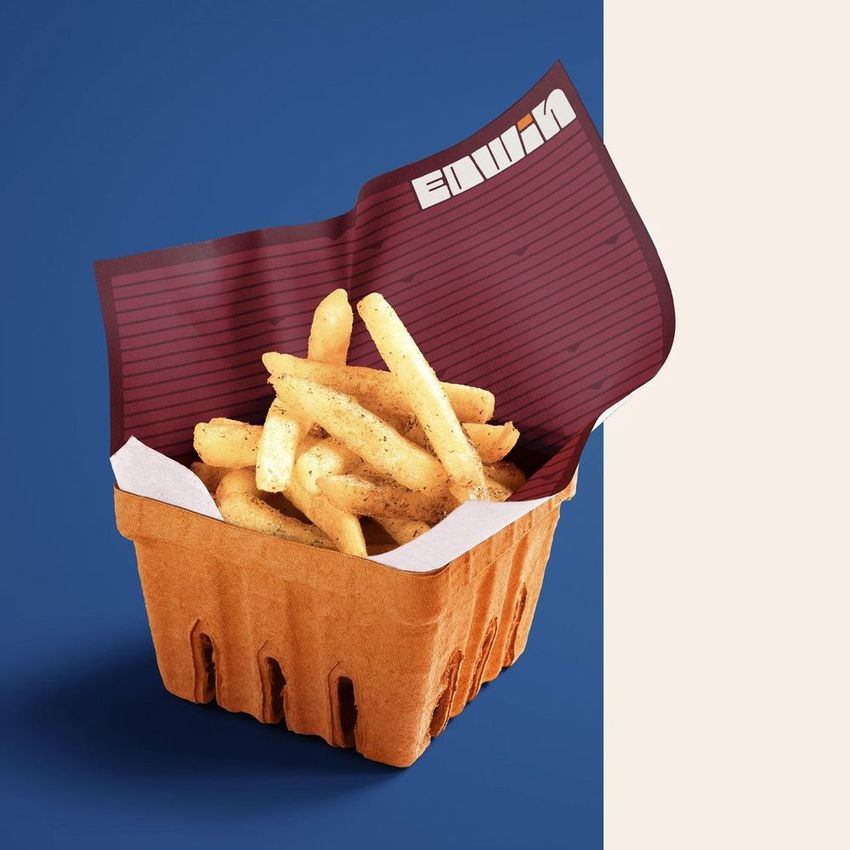 French fries served in a brown paper container with a maroon food safe paper mockup featuring a lined design and text overlay.