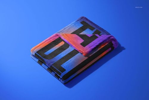 Fleece blanket mockup showing a folded textile with large black lettering and vibrant gradient colors, top view.