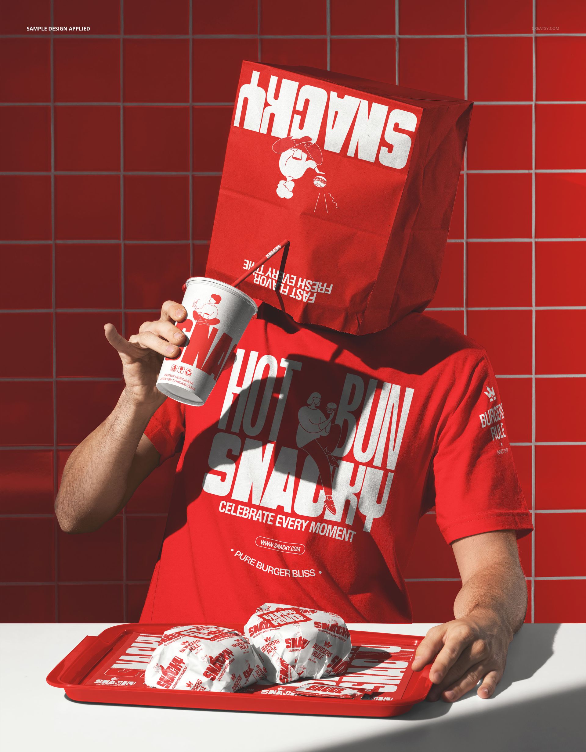 Fast food mockup scene showing a man with a branded paper bag over his head, red tray, wrapped burgers, and soda cup.