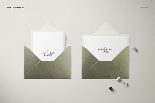 Mockup of two open C6 envelopes with greeting cards, metallic finish, displayed with small cylindrical objects on a pale background.