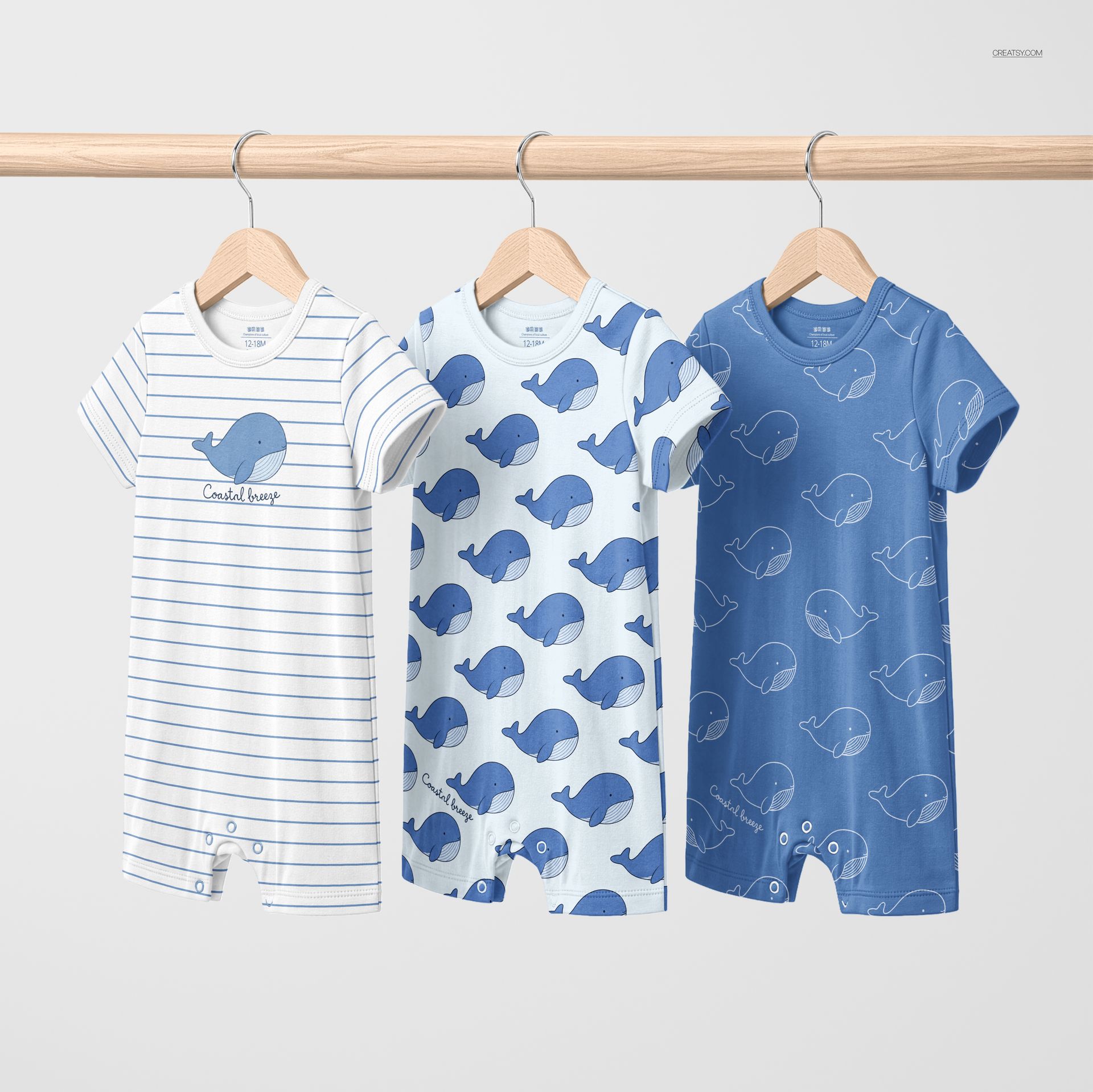 Three short-sleeve baby romper mockups in blue and white, displayed on a wooden rail against a plain background.