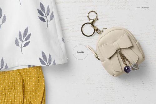 Top view of a baby summer set mockup featuring a white shirt with leaf patterns, yellow shorts, and a beige mini bag with a bow.