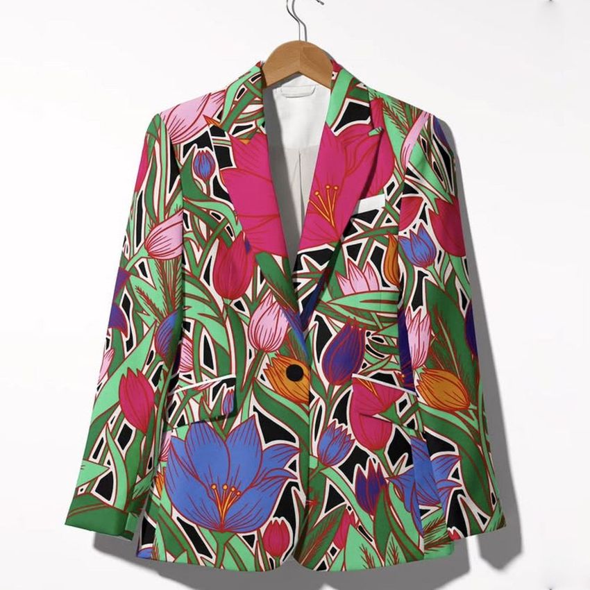 Blazer mockup featuring a vibrant floral pattern with pink, purple, and red tulips on a green and black background, hanging on a wooden hanger.