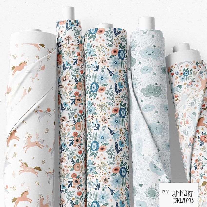 Fabric rolls mockup featuring five upright rolls with pastel floral, animal, and cloud patterns on a white background.