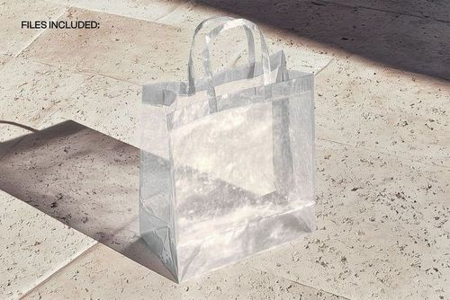 Clear plastic shopping bag mockup placed on a textured beige tile surface, illuminated by natural light.