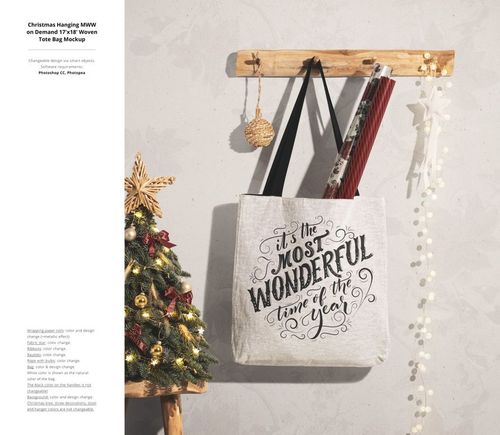 Front view of a Christmas-themed tote bag mockup hanging on a wooden rack, with gift wrap rolls and festive decor.