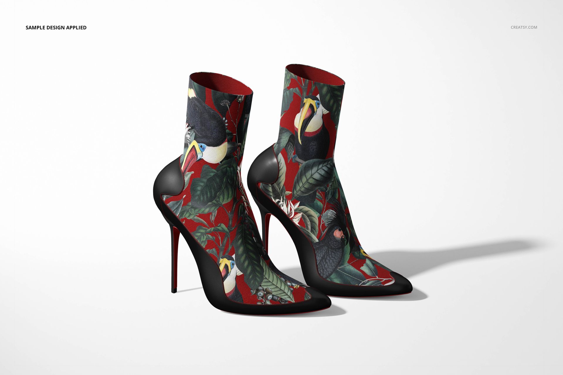 PSD mockup of high-heeled ankle boots covered in a colorful jungle motif, showing details of birds and leaves in rich tones.