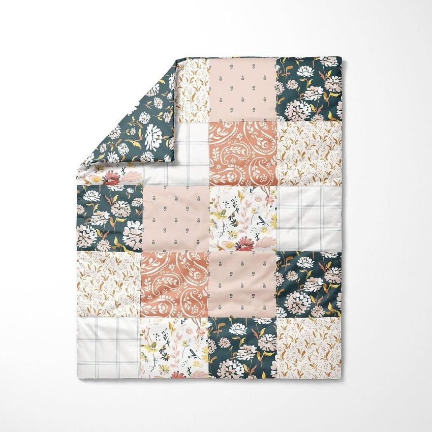 Baby patchwork quilt mockup featuring a folded corner, arranged with floral, paisley, and plaid patterns on a white background.