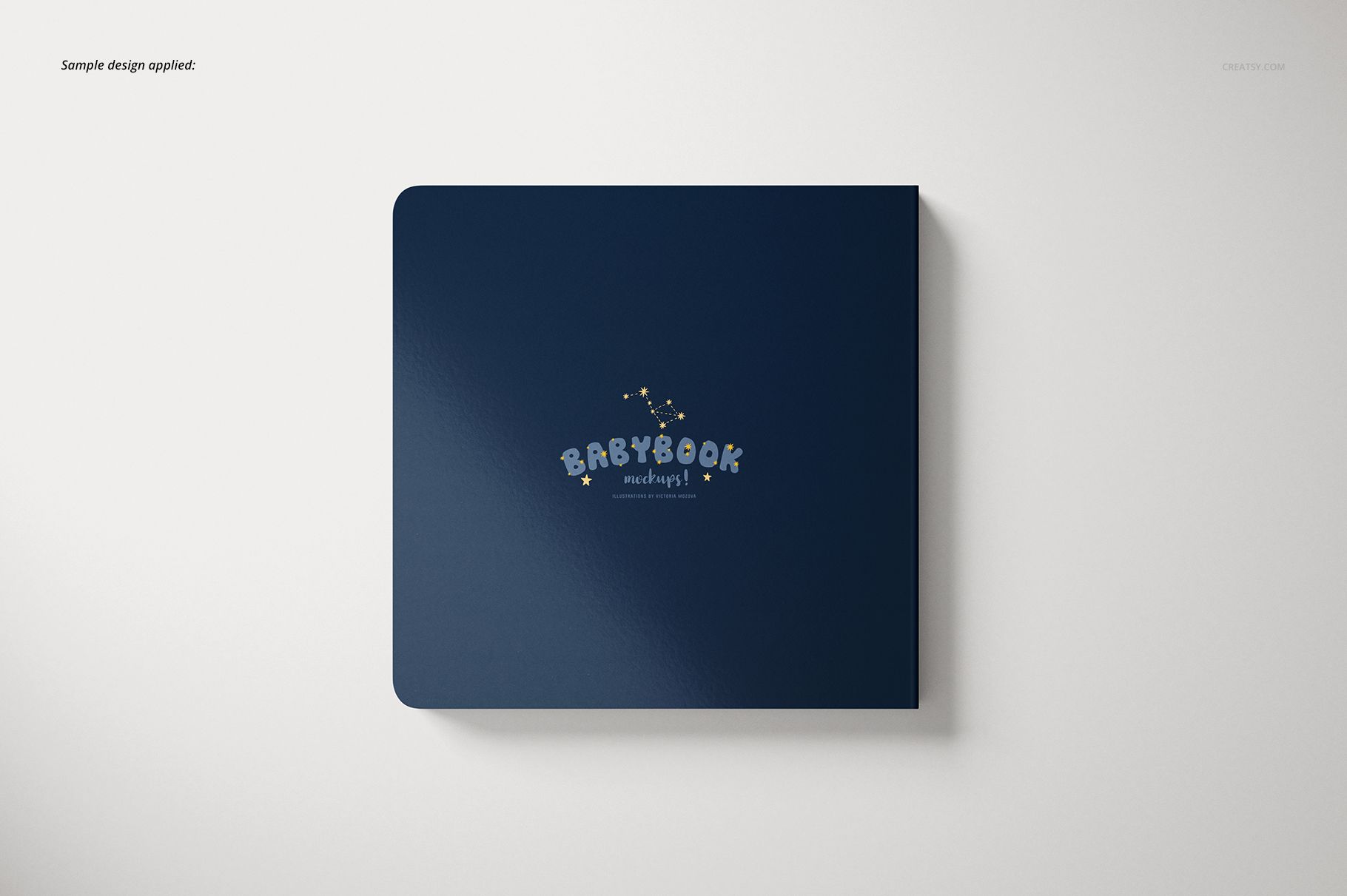 Cardboard baby book mockup showing a navy blue cover with rounded edges and whimsical lettering, viewed from above.
