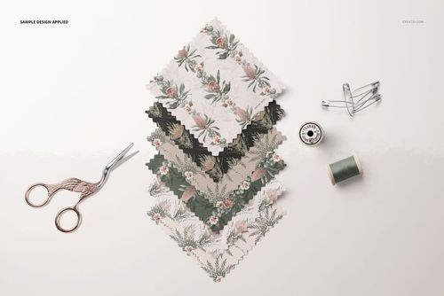 Fabric swatches mockup showing layered textiles with muted floral prints, viewed from above with scissors and thread.