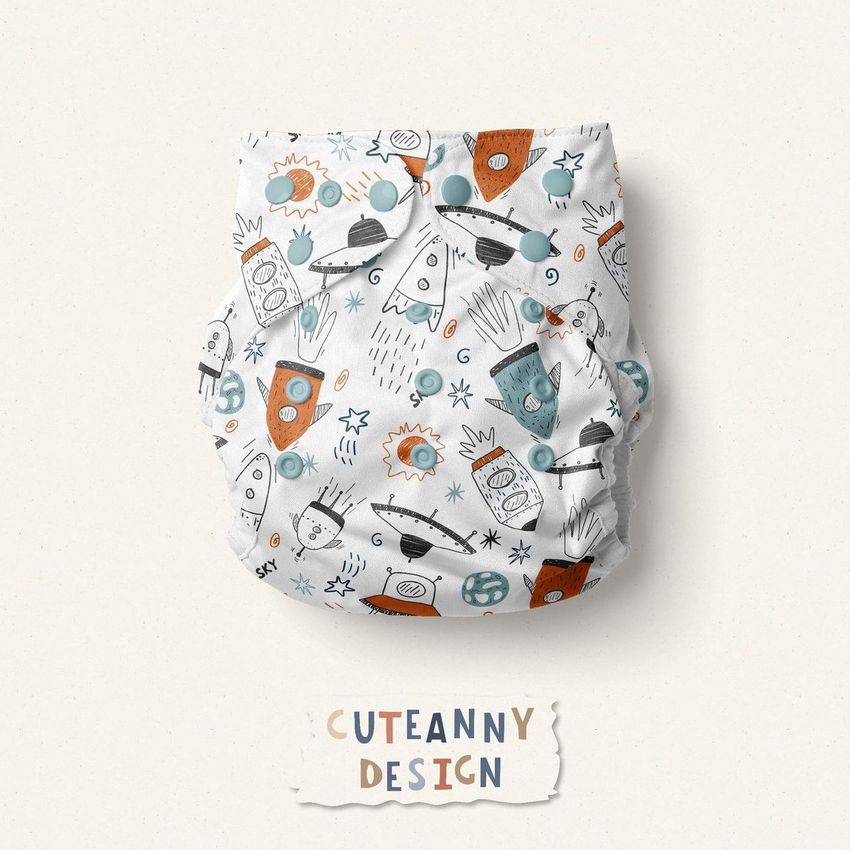 Reusable baby cloth diaper mockup featuring a playful space-themed pattern with rockets, stars, and planets in orange, blue, and gray.