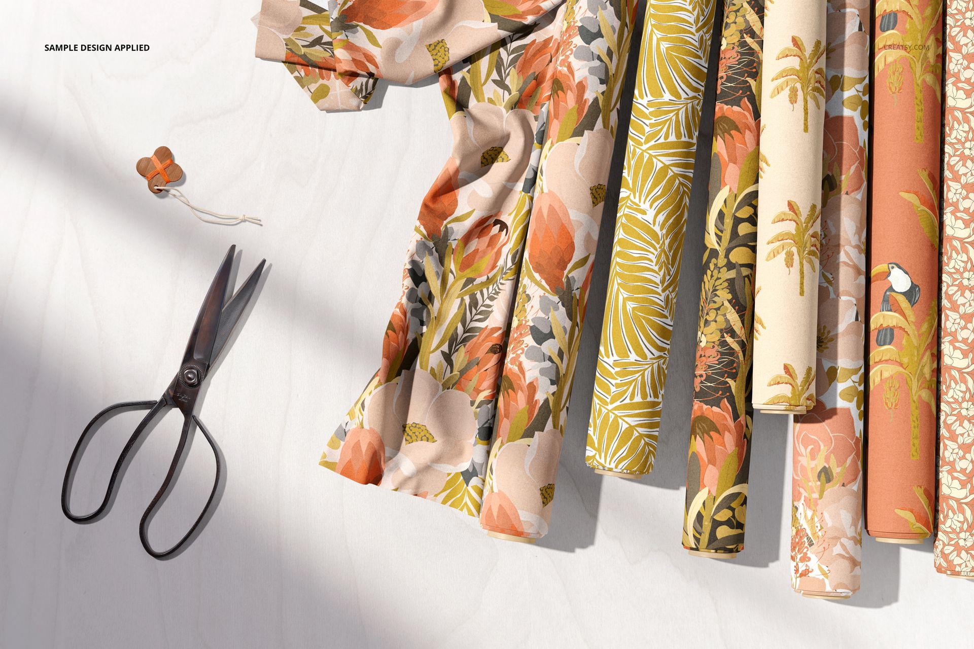 Several fabric rolls with botanical and floral patterns in warm earth tones displayed on a light surface, top view.