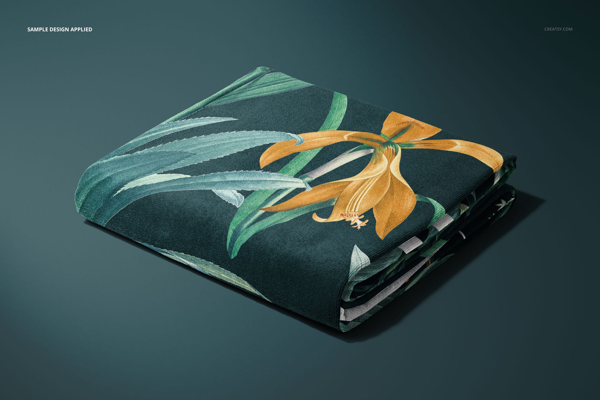 Beach towel mockup with tropical leaf and yellow flower design, displayed folded from a front angle on a dark backdrop.