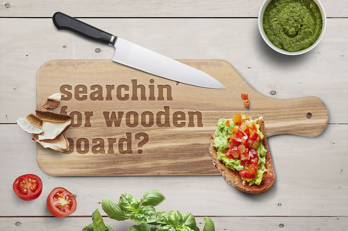 Top view of engraved wooden board mockup with knife, sliced bread, avocado toast, tomatoes, and green herbs.