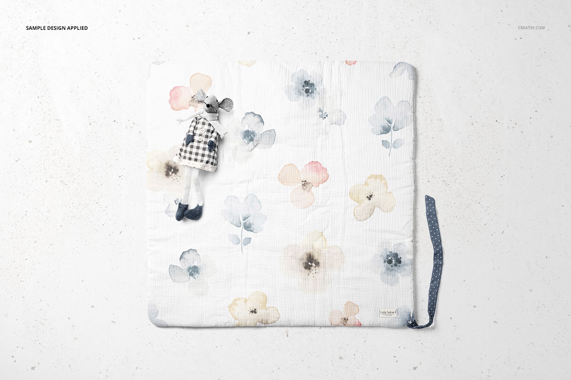 Top view of a newborn swaddle wrap mockup with pastel floral patterns and a small toy mouse on a light surface.