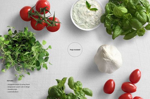 Top view of circular and rectangular glass cutting board mockup surrounded by tomatoes, garlic, herbs, and tzatziki on a light background.