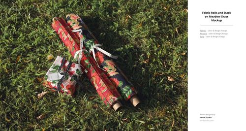 PSD mockup showing colorful flower print fabric rolls and a fabric stack placed on outdoor grass surface.